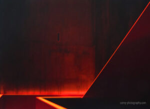 Galerie Ahlemann zeigt ein abstraktes Foto von Jochen Cerny auf dem in schwarzen, roten und gelben Farbtönen der Ausschnitt eines Treppenhauses zu sehen ist.