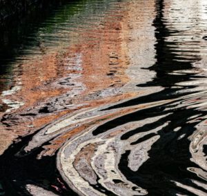 Galerie Ahlemann zeigt ein abstraktes Foto des Fotokünstlers Mick Schäfer aus der Serie "Reflecting Venice" auf dem Wasserreflektionen in überwiegend hellbraunen, grauen und schwarzen Farbtönen zu sehen sind.