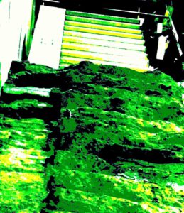 Galerie Ahlemann zeigt ein abstraktes Foto von Nicki Garz aus der Konzeptreihe "9 /11", auf dem in überwiegend grünen Farbtönen die Ruine einer Treppe zu sehen ist.
