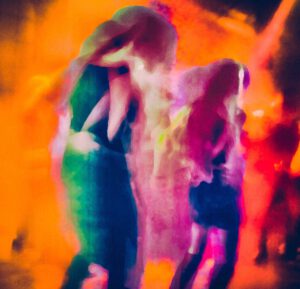 Galerie Ahlemann zeigt ein abstraktes Foto der Künstlerin Suria Kassimi aus ihrer Serie "Citylights" auf dem in überwiegend rötlichen Farbtönen zwei abstrahierte Frauensilhouetten zu sehen sind.